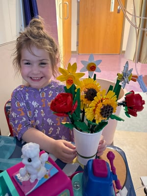 A little girl named Sophie holding a bouquet of Lego flowers while in the hospital facing leukemia.