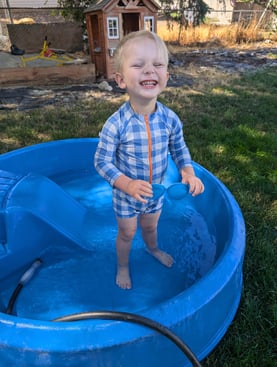 A Pinky Swear All-Star kid who has faced cancer smiling in a pool in his backyard.
