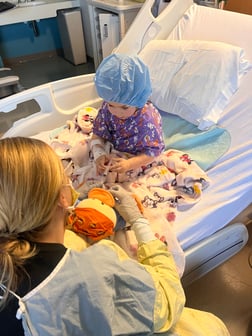 A little girl with AML providing medical care for her chemo duck with a nurse in the hospital.