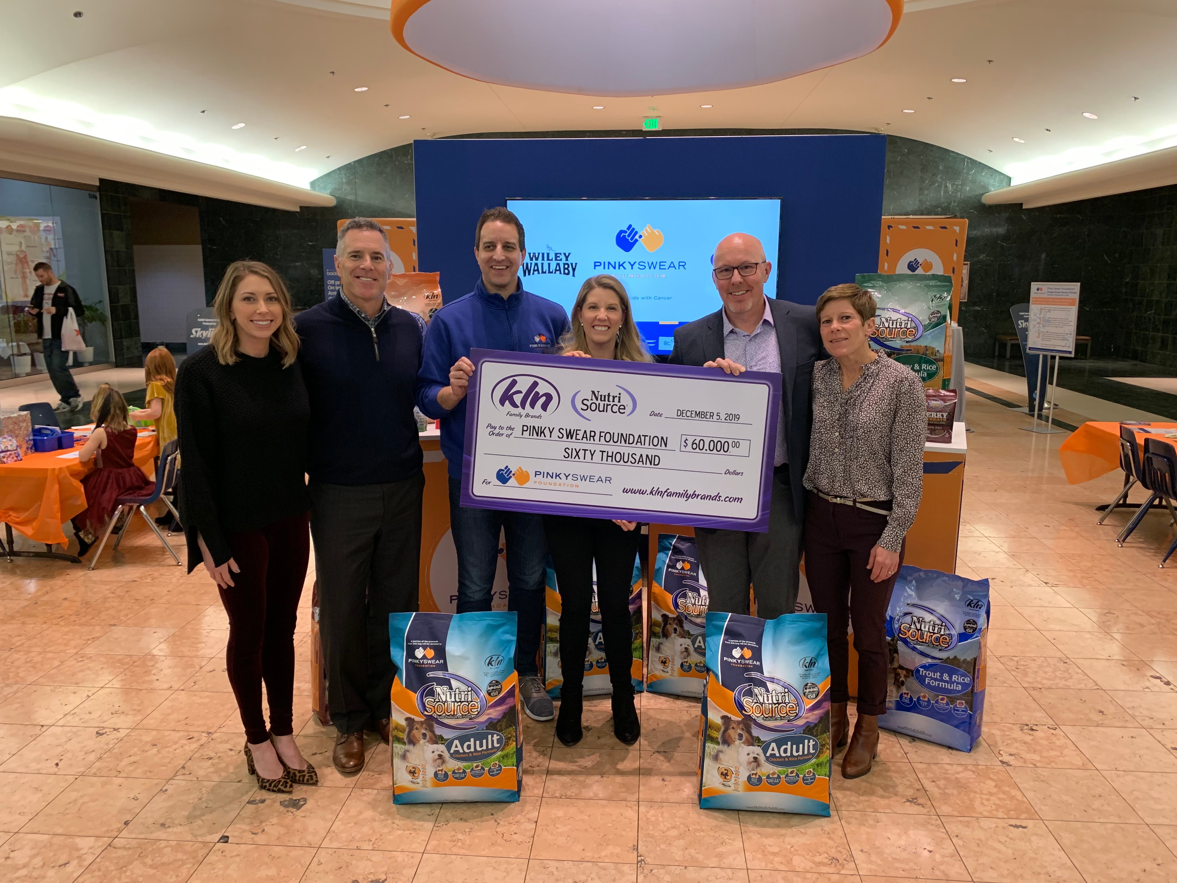 KLN Family Brands and Nutri Source giving funds to Pinky Swear Foundation through a check to help kids with cancer and their families.