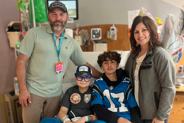 River and his family sitting on his hospital bed on his birthday