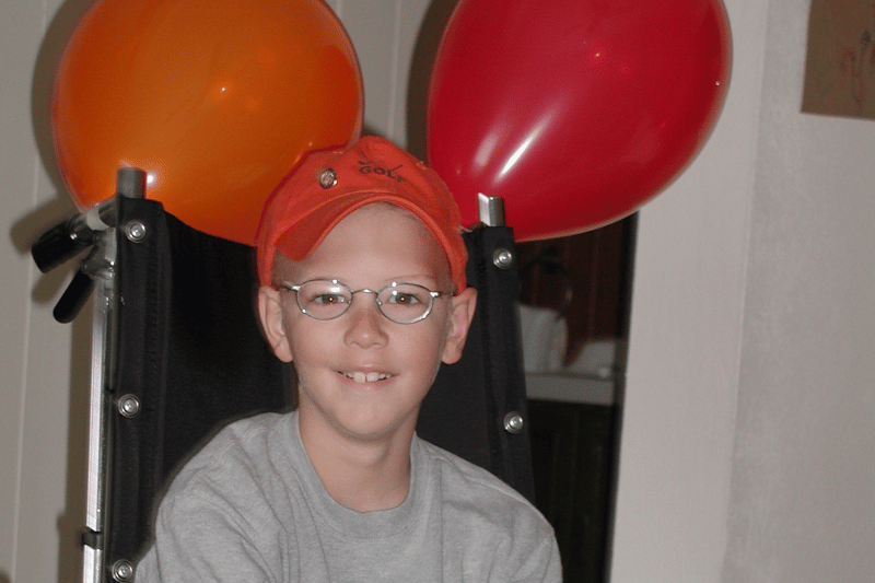 Pinky Swear Founder, Mitch, in a wheelchair with balloons tied to his chair.