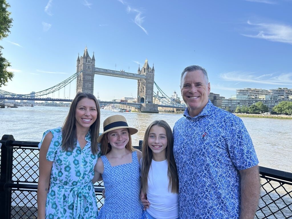 A Pinky Swear Board member and his family standing in front of a bridge.