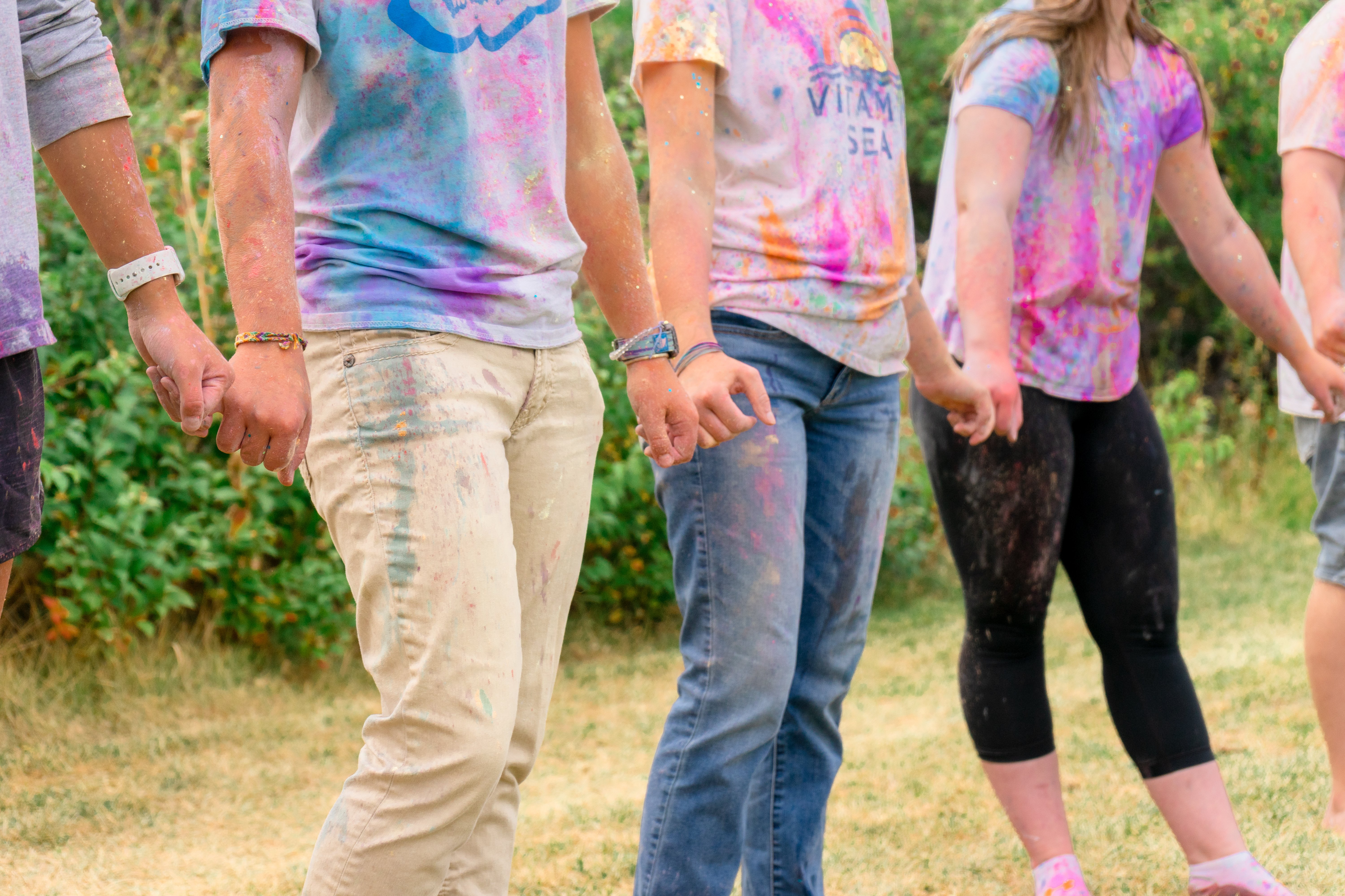 A group of college students doing a pinky swear chain with messy shirts during a Cancer Is Messy event. 