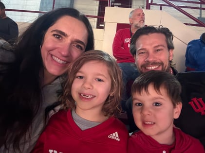 A selfie of Katie with her partner and two children at a sporting event. 