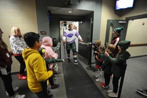 Kids form two lines as a Minnesota Wild Hockey player gives fist bumps before heading onto the ice before the Hockey Fights Cancer game in Minnesota.