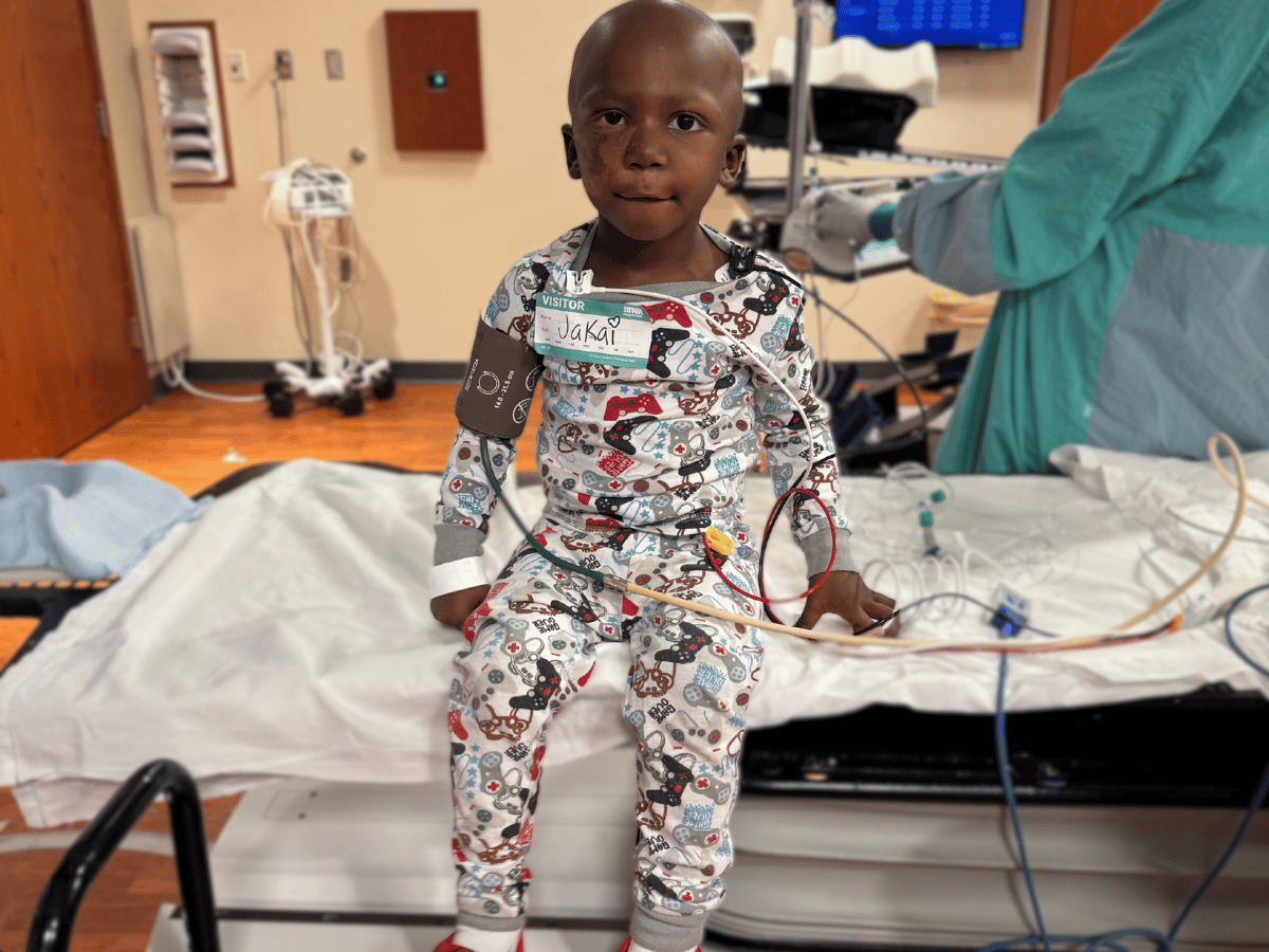 A little boy sitting on a hospital table hooked up to wires