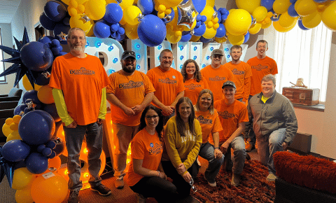 A team of people wearing bright orange Dean Snyder Construction shirts after volunteering at Radiothon.