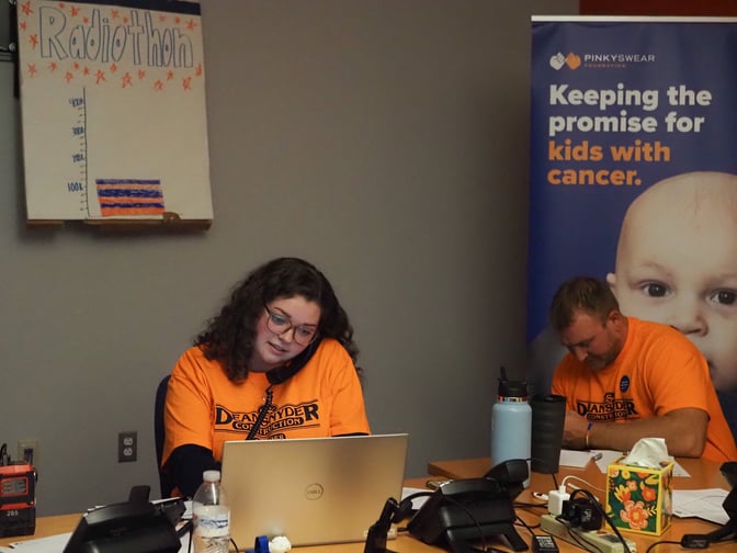 A volunteer from Dean Snyder Construction answering the phone at the Pinky Swear radiothon to raise money for kids with cancer.