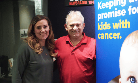 Two people standing in front of a childhood cancer sign.