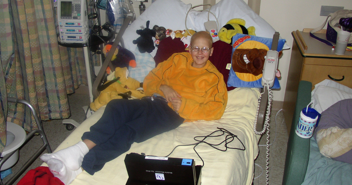 A little boy laying in his hospital bed surrounded by stuffed animals. Mitch was the reason Pinky Swear Foundation started to help kids with cancer and their families financially.