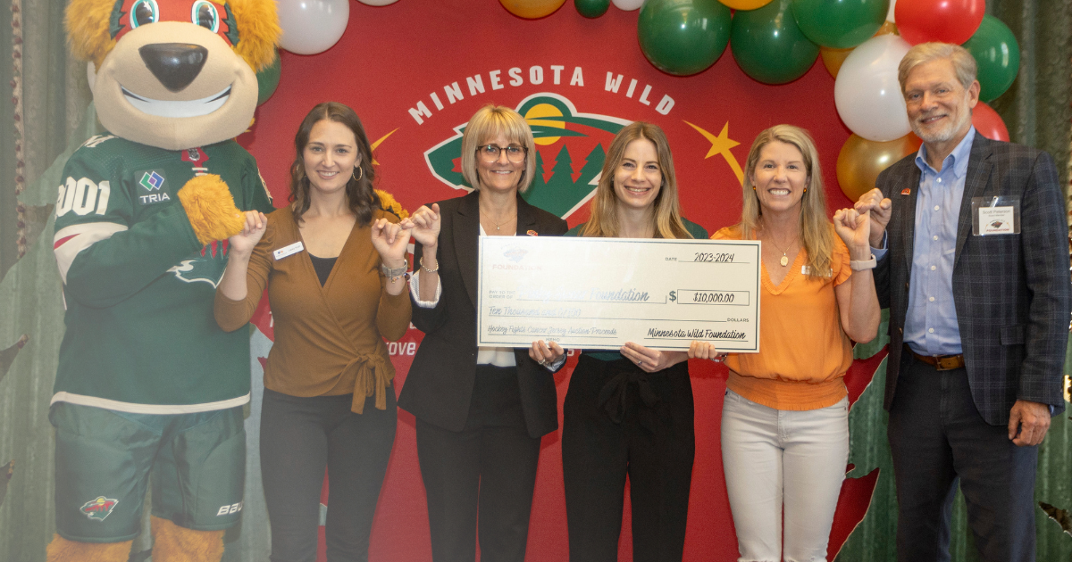 Pinky Swear Foundation team members receiving a check from the Minnesota Wild Foundation to support kids with cancer and their families.