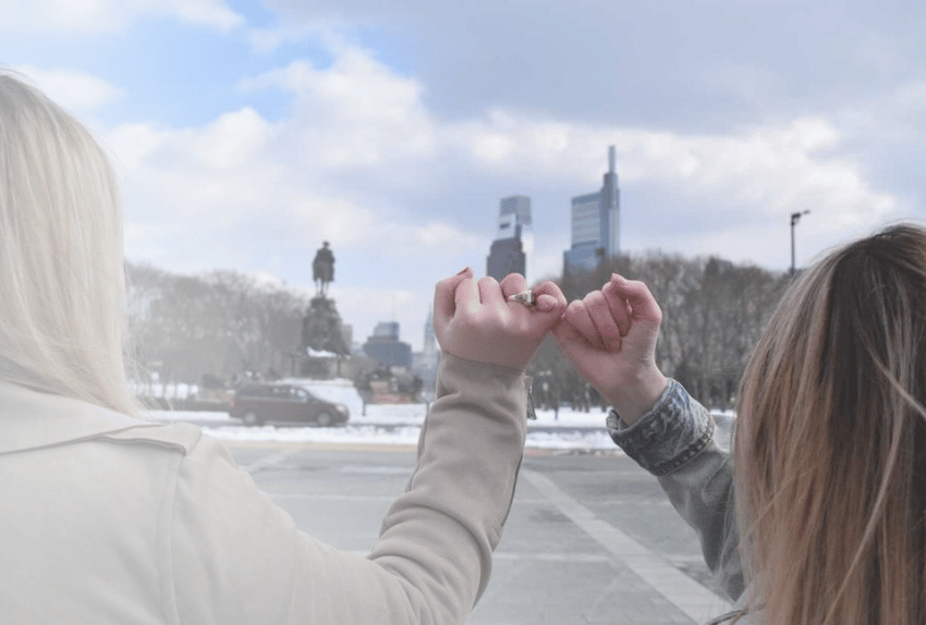 Two Pinky Swear Pack members doing a pinky swear with their city in the background.