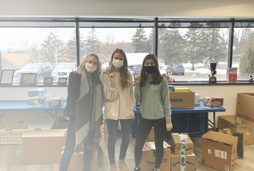 Three women wearing masks in the Pinky Swear office volunteering.