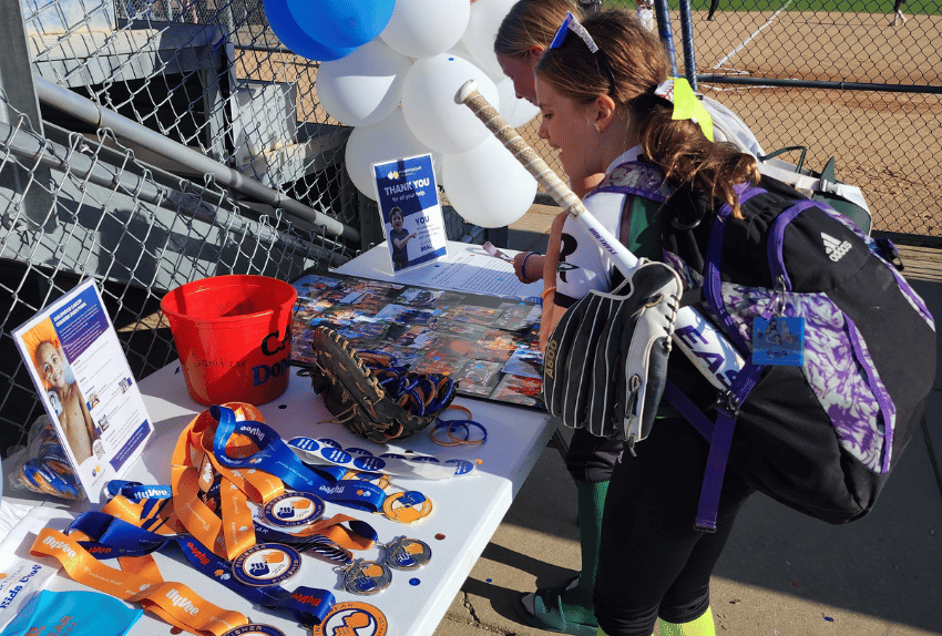 A softball player looking at the table with information about Pinky Swear Foundation.