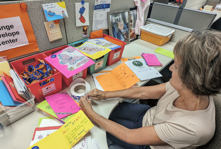 A Pinky Swear volunteer putting stickers on Letters of Encouragement
