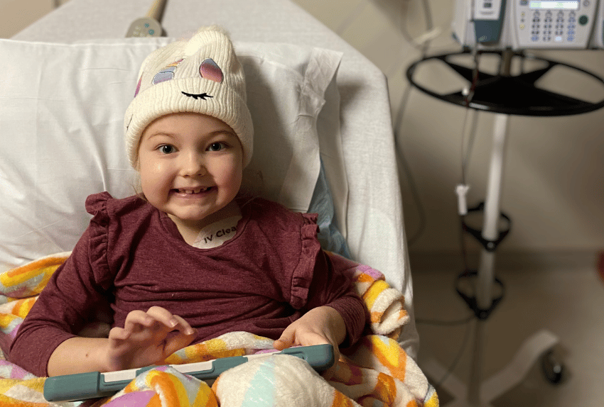 A little girl named Winnie in the hospital wearing a hat during cancer treatment.
