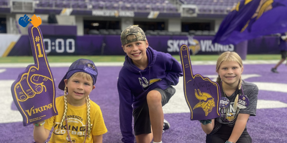 A boy named Ivan and his two siblings on the field at a Minnesota Vikings game. Ivan and his family received support from Pinky Swear Foundation during his childhood cancer journey.