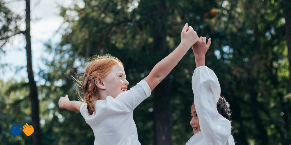 Two girls doing a pinky swear while jumping