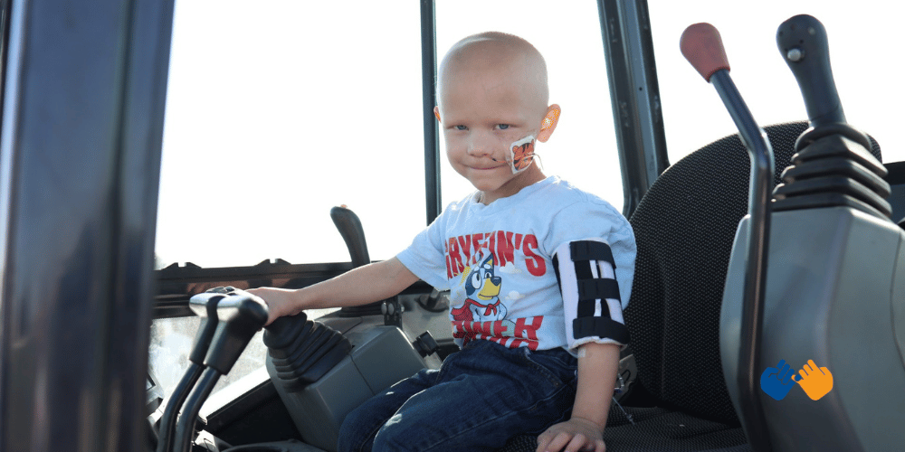 A little boy named Gryffin who is facing a rare and aggressive cancer diagnosis sitting in a tractor looking at the camera.