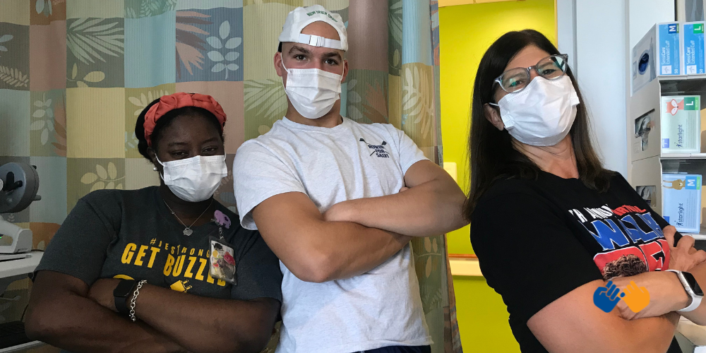 A boy named John who faced a brain tumor smiling under masks with his nurses