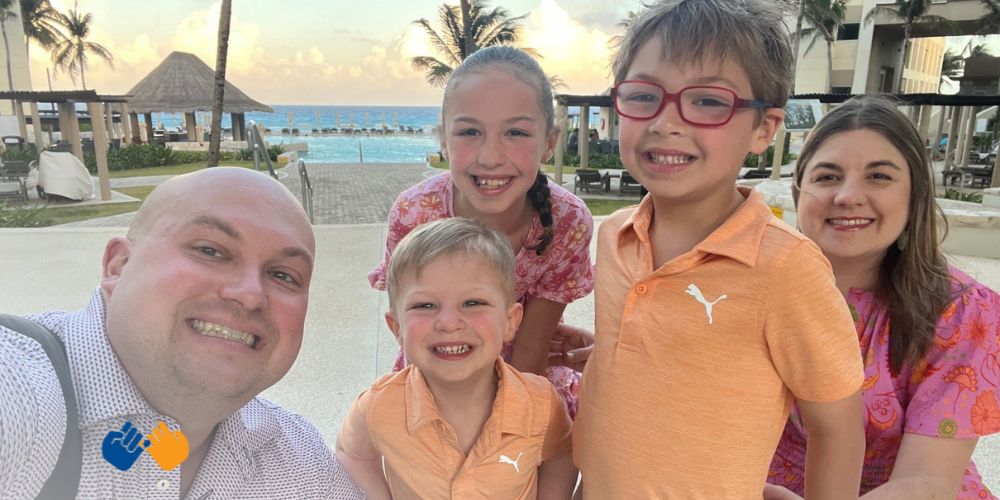 Board Member Mike and his family smiling for the camera standing on the beach.