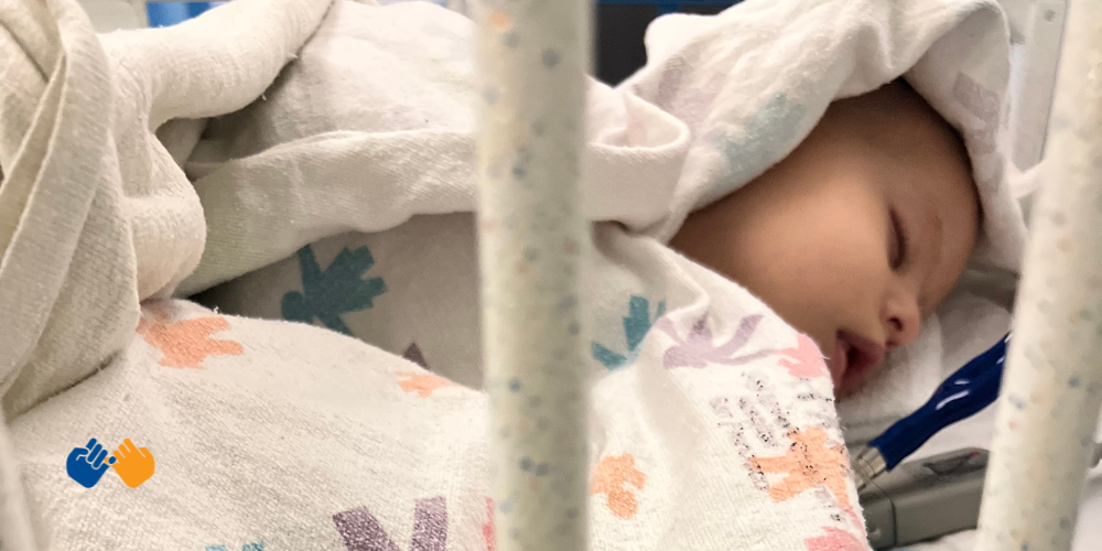 A little girl named Nora sleeping in a hospital crib